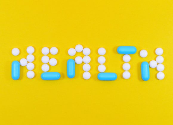 White and Blue Health Pill and Tablet Letter Cutout on Yellow Surface